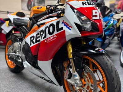 Pre‑owned Honda CBR sport motorcycle with Repsol racing livery parked indoors at a motorcycle dealership.