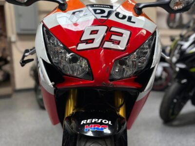 Front close‑up of a sport bike featuring Repsol racing‑style livery and twin headlights parked indoors at AK Motorcycles.