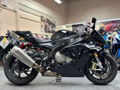 Black BMW S1000RR sport motorcycle side profile parked indoors with other bikes in background