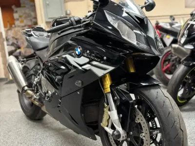 Close-up of a black BMW sport bike parked indoors, showing front fairing, headlight, and tire.