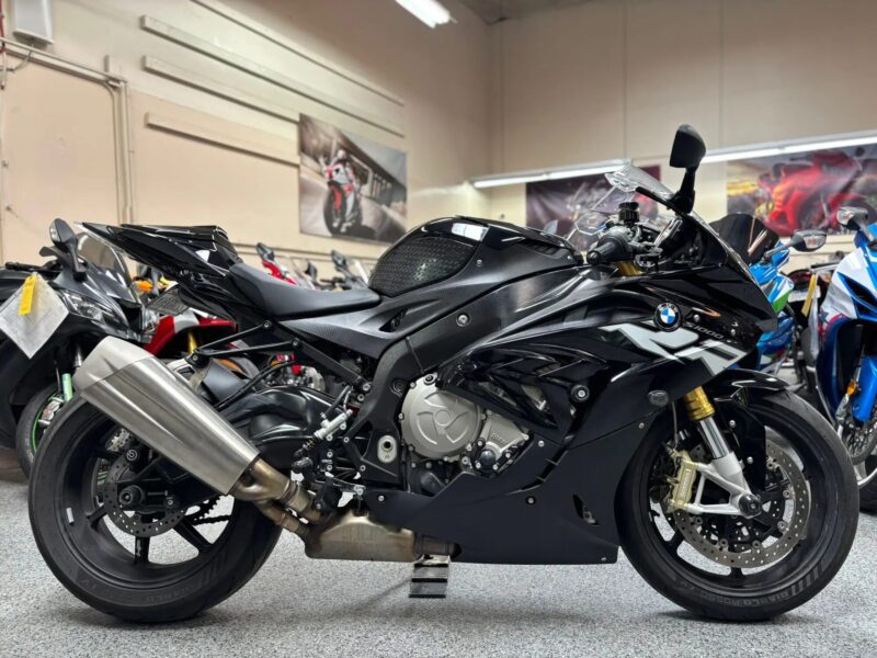 Black BMW S1000RR sport motorcycle side profile parked indoors with other bikes in background